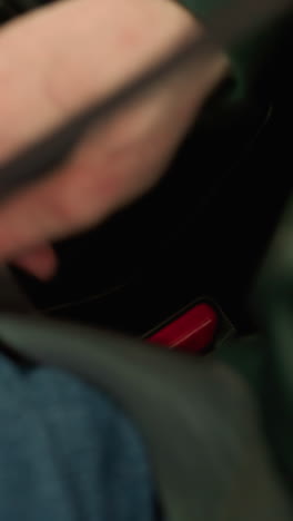 fotografía en primer plano de una persona en un coche desabriendo el cinturón de seguridad, centrándose en la mano que suelta el cinturó