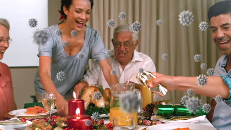 animation of covid 19 cells moving over multi generation family sitting at table for christmas meal