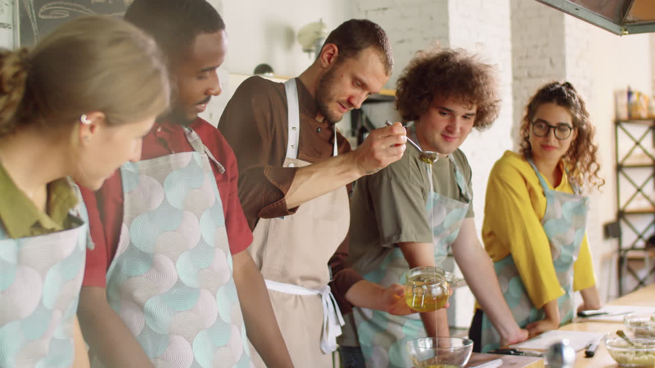 요리사는 그에 을 부어 요리 마스터 클래스에서 학생들과 이야기합니다.