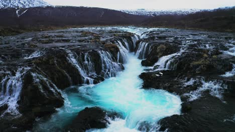 spectacular flowing bruarfoss waterfall down the rocks during cloudy day