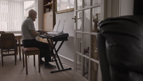 senior man playing piano at home