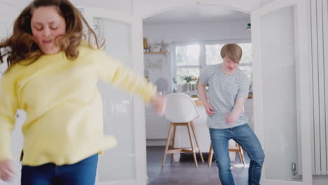 una pareja joven con síndrome de down que se divierten bailando juntos en casa.