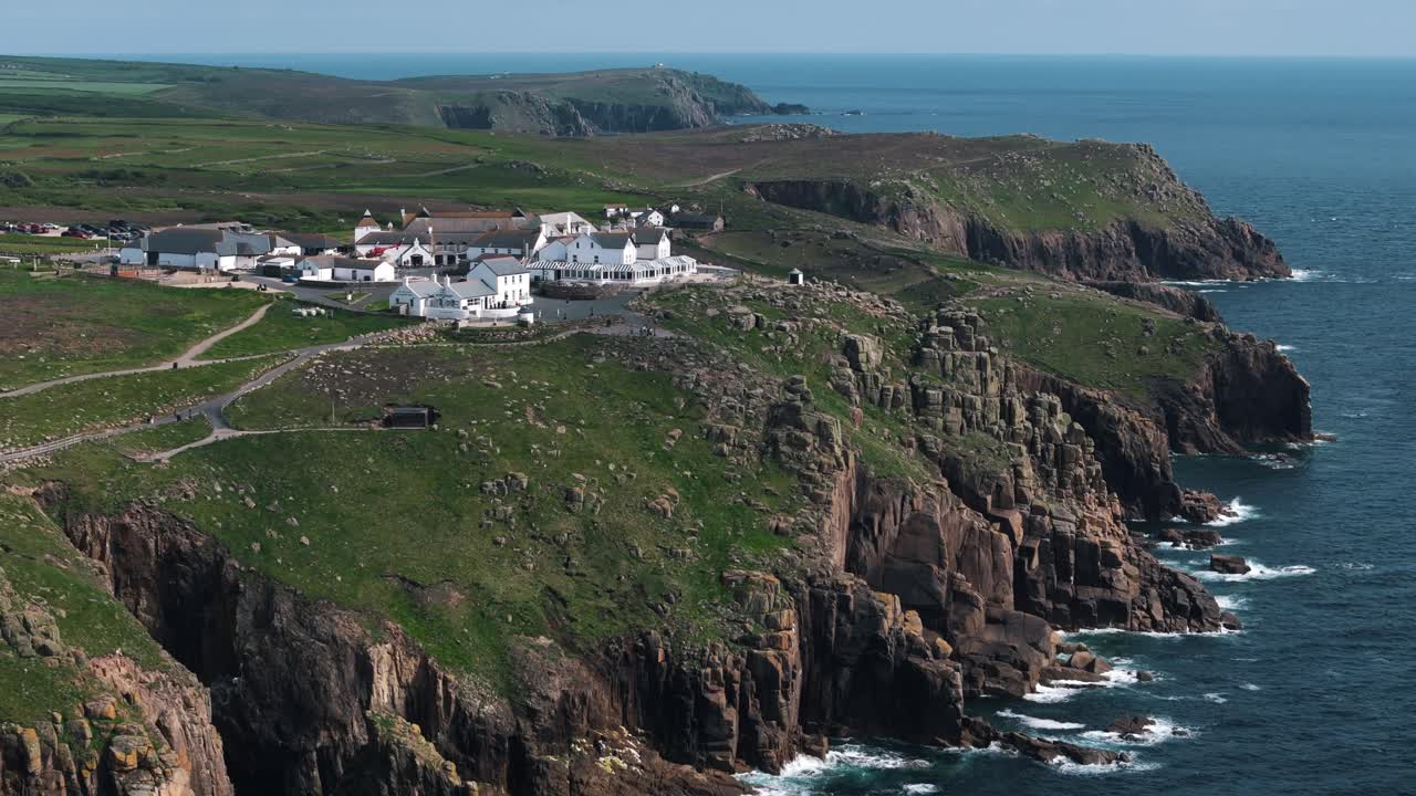 Drone circles building near Lands End Cornwall with cliffs and ocean in backdrop, natural background as water meets rock