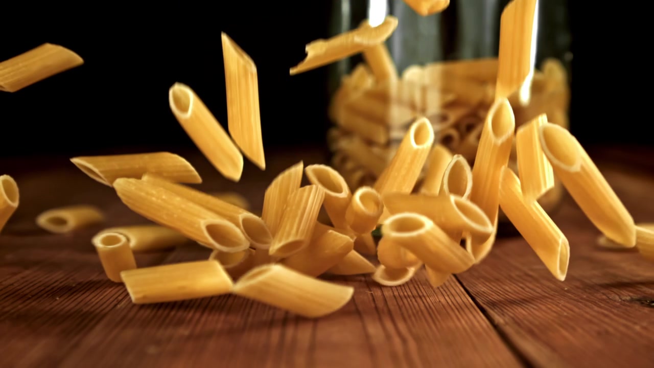 Penne che cadono al rallentatore su un tavolo di legno