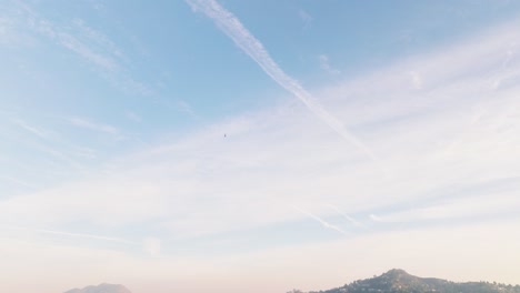 Drone-Shot-of-Sunny-LA-in-Daytime,-Helicopter-in-Bright-Blue-Sky-with-Businesses-and-Luxury-Homes-Below