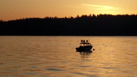 a lone motor boat slowly bobbing in the morning waves, anchored in puget sound, vashon island in the background, golden sunrise, gig harbor, washington, peaceful