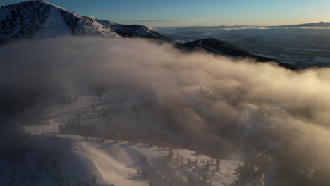 Cinematic-Aerial-View-of-Clouds-Above-Snow-Capped-Mountain-Hills-at-Sunset