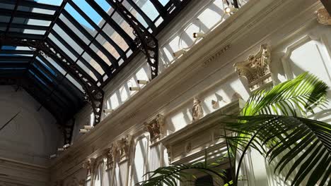 a sunlit, restored pereira palace interior with intricate white decor and glass ceiling