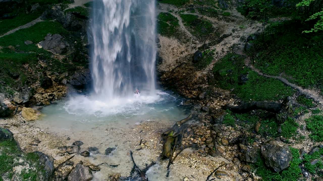 el hombre con barba está haciendo meditación de cascada bajo una gran cascada.