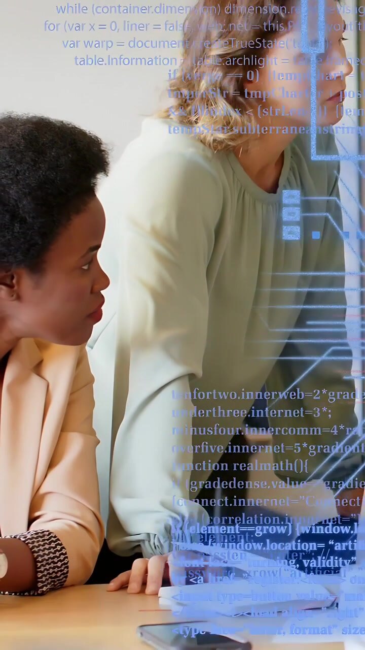 Vertical video: Coworkers leaning, tapping notebook and phone, initiating tech overlay for analysis