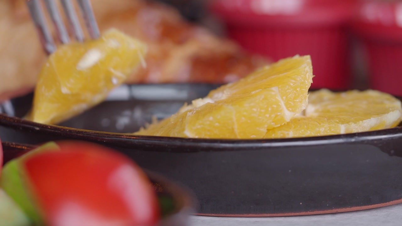 Fork Picking Up a Peeled Orange Slice from a Bowl