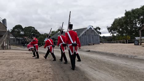 soldiers in red uniforms marching through town