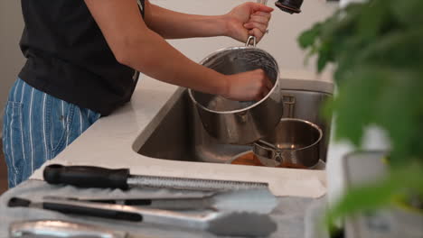 Woman washing dishes in kitchen sink housework chores bright home