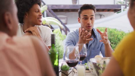 Happy-latin-man-talking-with-friends-at-dinner-party-on-patio