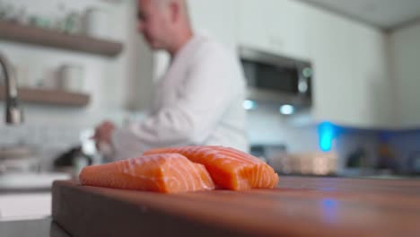 a low-angle shot of a chef cleaning their work space, with a slab of fish resting on the cutting board, highlighting both cleanliness and food preparation in a professional kitchen setting.