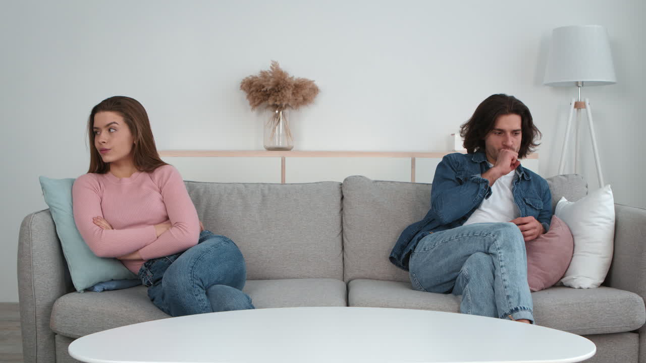 una pareja discutiendo en un sofá.