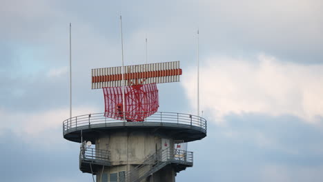 detailed view of airport radar system with red rotating antenna mounted on tall tower