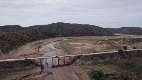 bridge over dry arade river and green hills in portugal, aerial pan