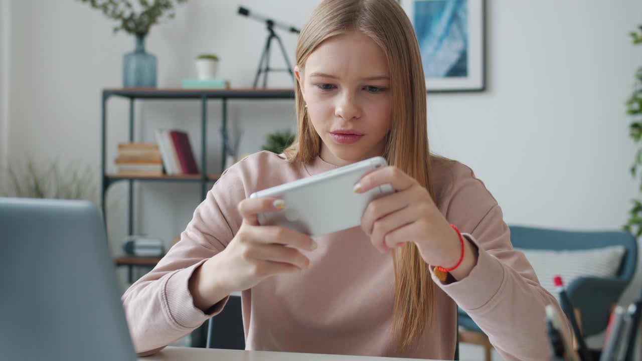 Teenage girl playing mobile game at home