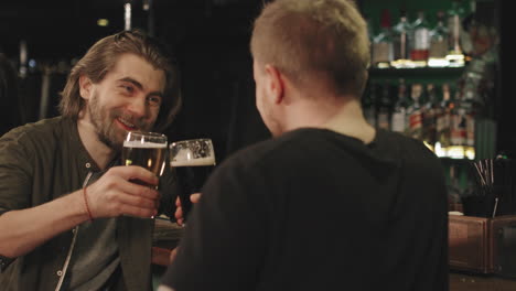 happy men toasting beer mugs at bar