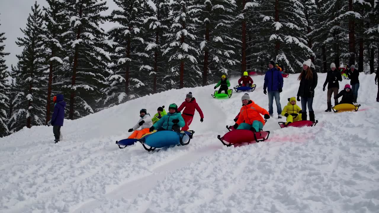 A lively video captures a group sledding down a snowy hill, shot from a low angle