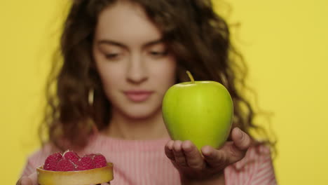 Young-woman-holding-apple-fruit-and-berry-cake-on-yellow-background