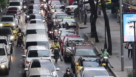 a busy urban street filled with cars, motorcycles, and buses during daylight hours.