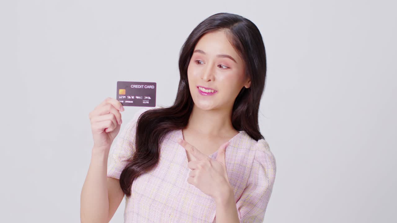 행복하고 매력적인 아시아 젊은 여성은 쇼핑과 지불을 위해 신용카드를 들고 색 배경에 분리된 미소를 짓고, 즐거운 예쁜 소녀는 온라인 쇼핑을 위해 은행 신용 카드를 사용합니다.