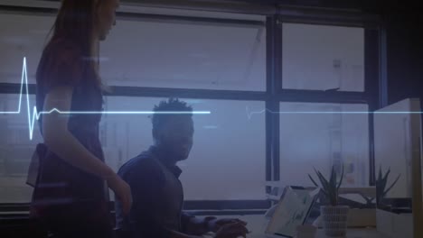 Glowing-blue-heart-rate-monitor-against-diverse-male-and-female-colleagues-discussing-at-office