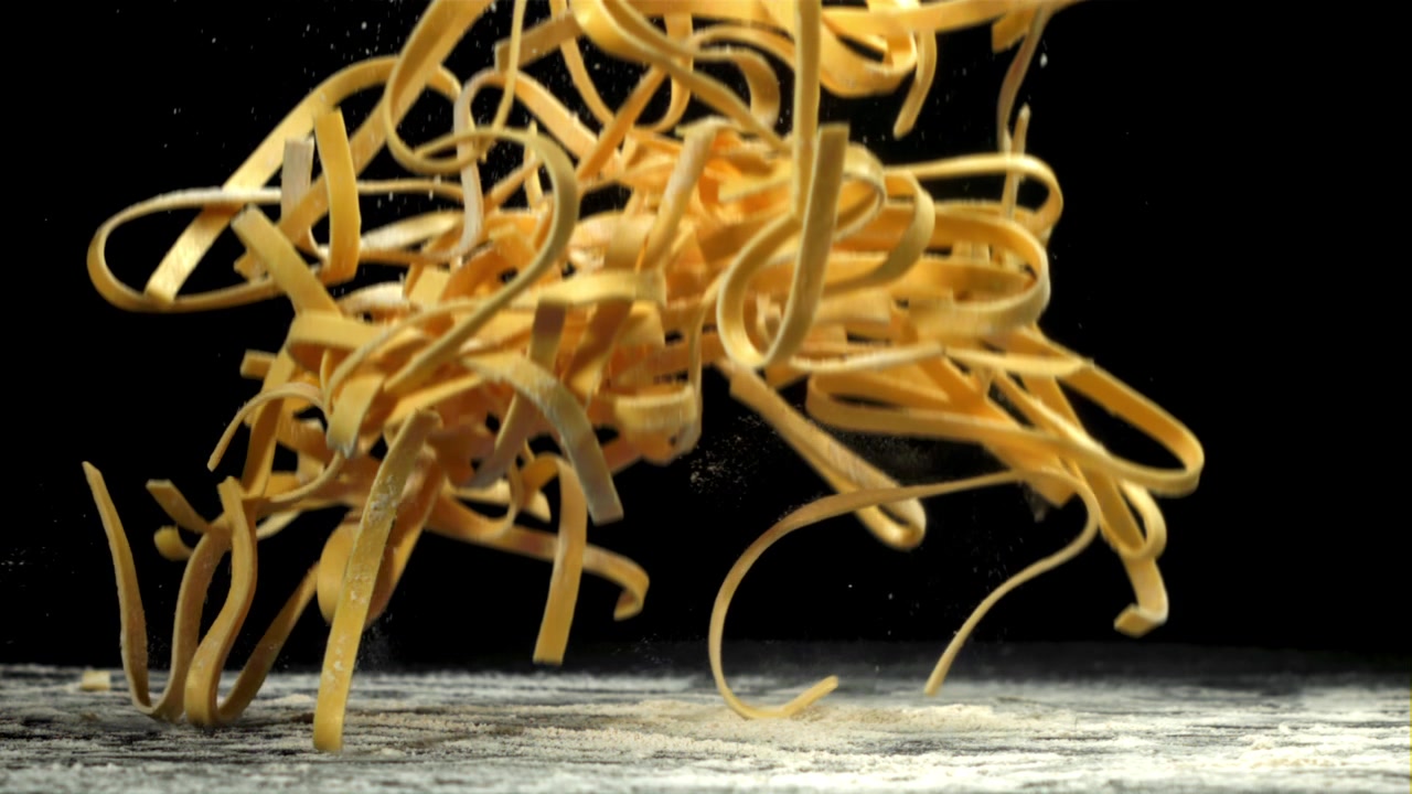 Pasta fresca cruda che cade su una superficie infarinata