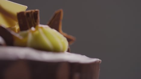 close up studio shot of freshly baked and decorated chocolate celebration cake revolving against black background 2