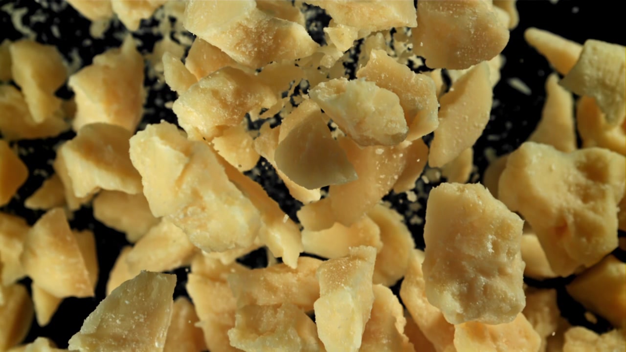 Parmesan Cheese Pieces Falling in Slow Motion on Black Background