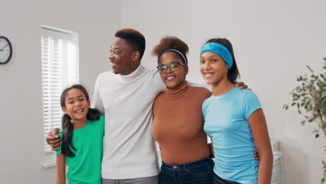 la familia feliz está pasando tiempo en un apartamento recién alquilado y comprado, están de pie en el medio de la sala de estar admirando la decoración, disfrutando de la mudanza pendiente, abrazos en grupo todos juntos