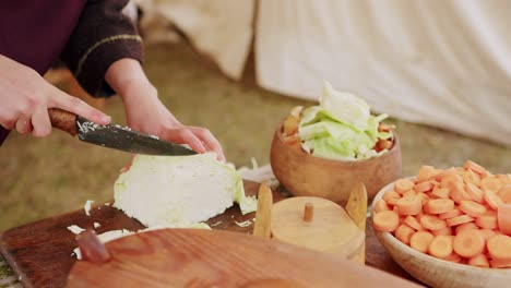 Woman-cutting-cabbage-to-prepare-a-traditional-dish-in-medieval-campsite