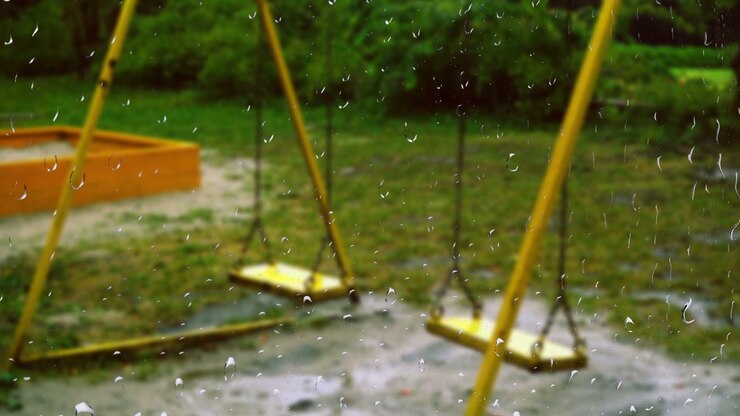 Swing during the rain. View from the window. Raindrops on the glass.