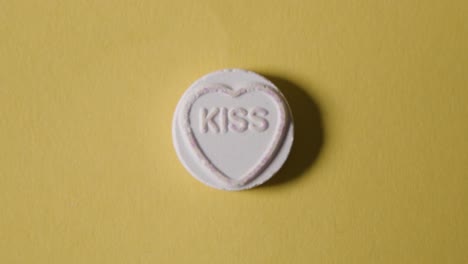 Heart-Candy-With-Word-Kiss-On-Yellow-Background