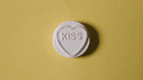 caramelo de corazón con beso de palabra sobre fondo amarillo
