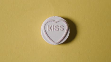 heart candy with word kiss on yellow background