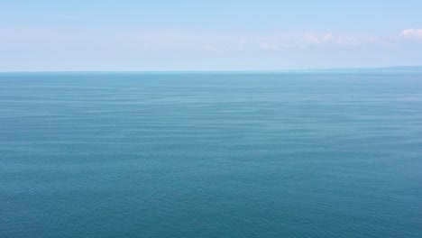 aerial flyover shot high above the open adriatic sea with only a tiny bit of land far in the distance