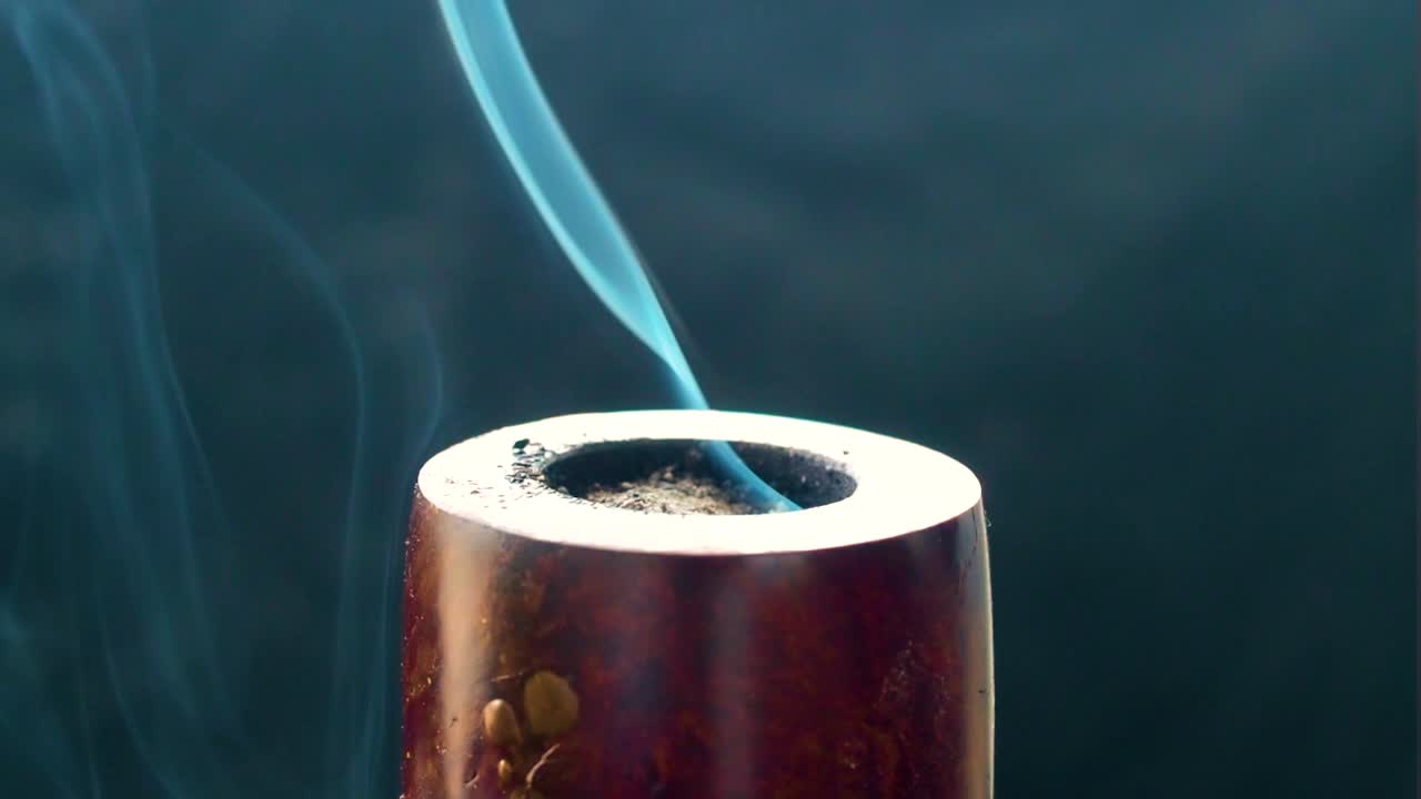 ambiente ahumado con una pipa de época que produce humo de la quema de tabaco de un color azul similar parecido a espíritus familiares chakras ritual espiritual lleno de ceniza dentro de una habitación oscura