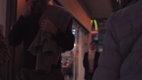 slow motion clip of people walking in a street of madrid in front of many shops, during evening hours.