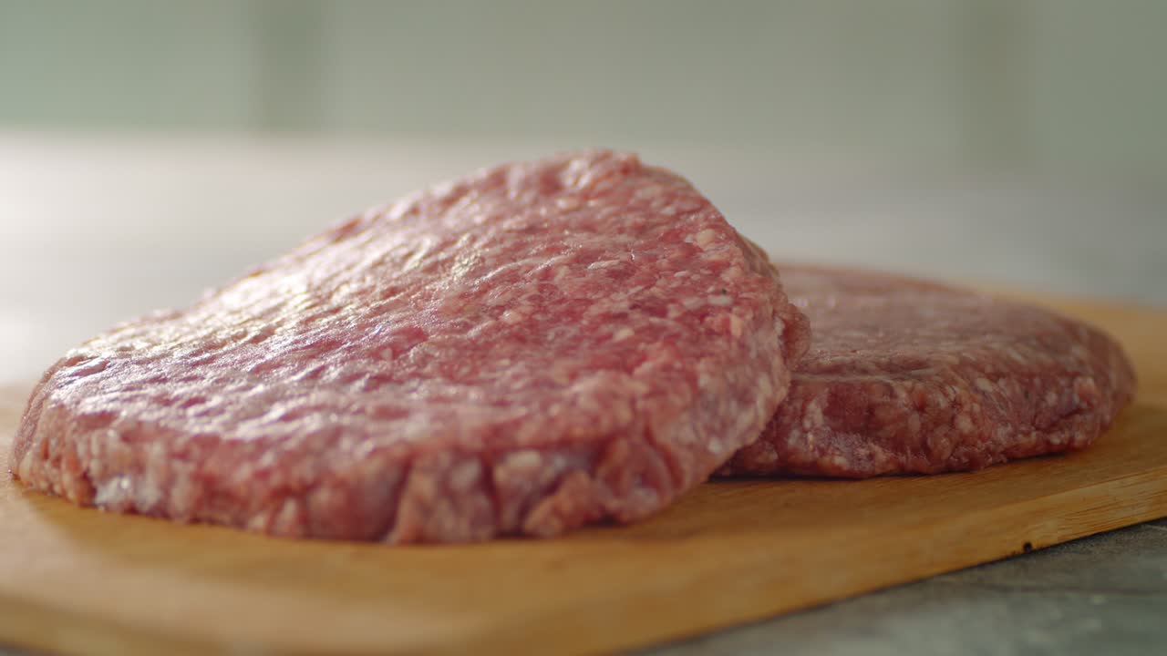 la carne cruda de la hamburguesa en una tabla de cortar gira lentamente.