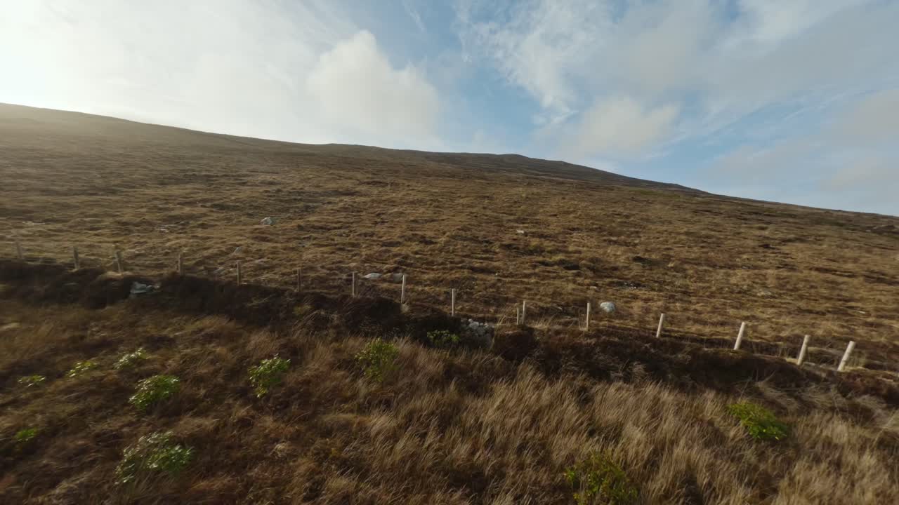 drone volando por una colina cubierta de hierba durante la última luz del día en la isla de achill, irlanda