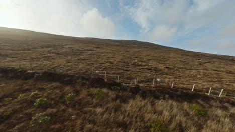 drone flying up a grassy hill during last light of the day on achill island, ireland