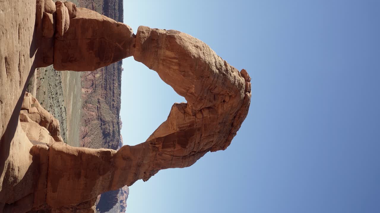 disparo vertical de mano de un hermoso arco de roca de arenisca roja natural causado por millones de años de erosión en un caluroso día de verano soleado en el sur de utah en una caminata de vacaciones