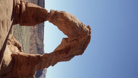 Toma-Vertical-De-Mano-De-Un-Hermoso-Arco-Natural-De-Roca-Arenisca-Roja-Causado-Por-Millones-De-Años-De-Erosión-En-Un-Caluroso-Y-Soleado-Día-De-Verano-En-El-Sur-De-Utah-En-Una-Caminata-De-Vacaciones