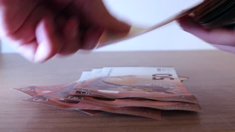 Close-up-shot-of-the-hands-of-a-rich-man-counting-50-euro-bills-or-notes-and-keeping-it-on-the-table-aside