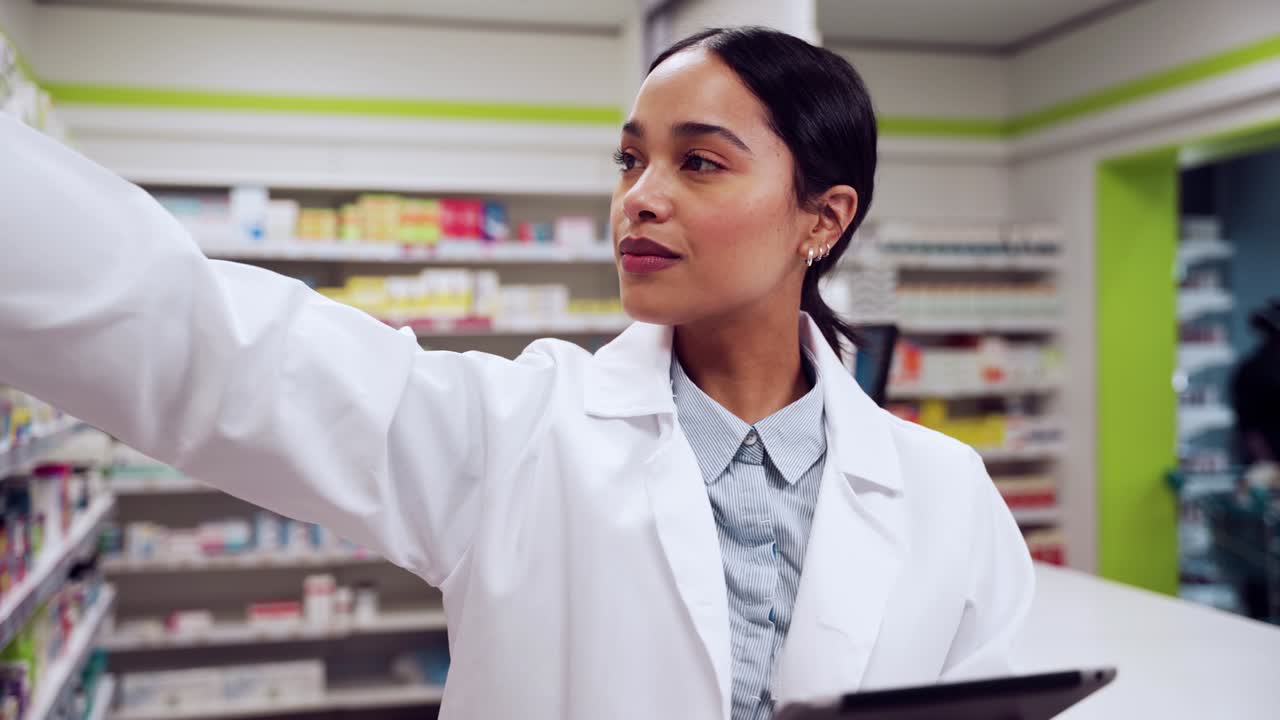 혼혈 여성 약사는 디지털 태블릿에서 약국 섬을 검색하고 있습니다.