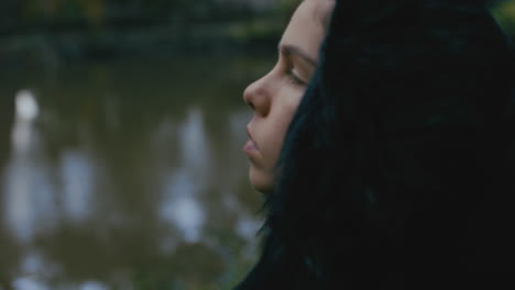 young woman sitting alone in park enjoying peaceful nature pond lonely teenage girl feeling depressed on cold cloudy day