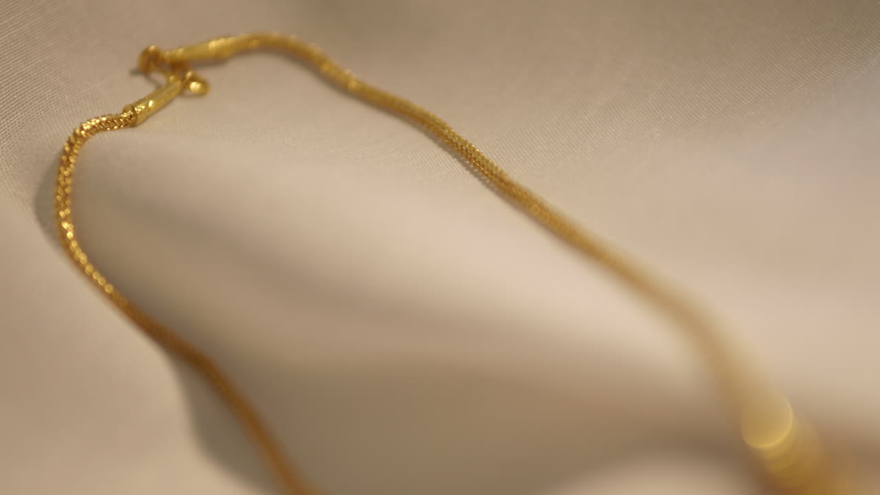 панорама с верхнего левого угла вниз к нижней правой стороне рамки, показывающая золотое ожерелье и сердечный медальон